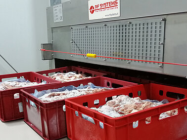 Image qui présente un système de décongélation par radiofréquence avec de grands bacs et de la viande congelée à l'interieur