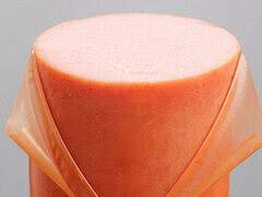 Photo d’une saucisse dont le boyau est en train d’être pelé, montrant le processus de retrait du boyau après le remplissage