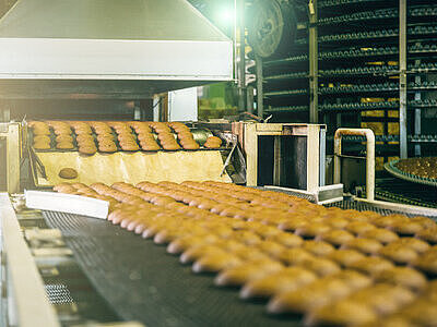Image d’un tapis de production recouvert de nombreuses brioches rondes, illustrant l’étape juste après la cuisson