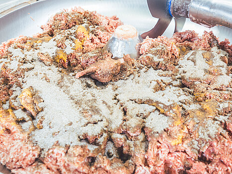 Photo d’un mélangeur contenant de la viande et plusieurs épices, illustrant le processus de préparation de la saumure et de mixage