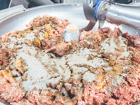 Photo d’un mélangeur contenant de la viande et plusieurs épices, illustrant le processus de préparation de la saumure et de mixage