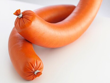 Image d’une saucisse avec des clips métalliques attachés à chaque bout, sur un fond simple