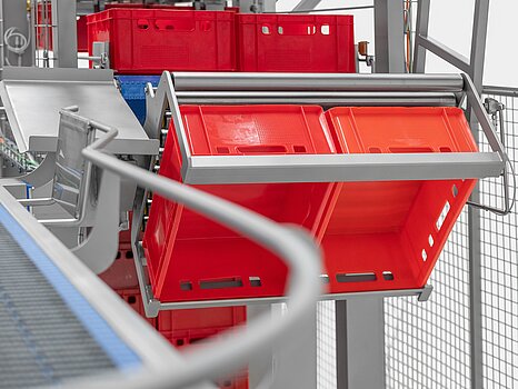 Photo montrant des bacs rouges en train d’être basculés par un système mécanique pour vider leur marchandise