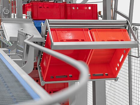 Photo montrant des bacs rouges en train d’être basculés par un système mécanique pour vider leur marchandise