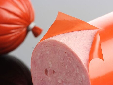 Photo d’une saucisse dont le boyau est en train d’être pelé, montrant le processus de retrait du boyau 