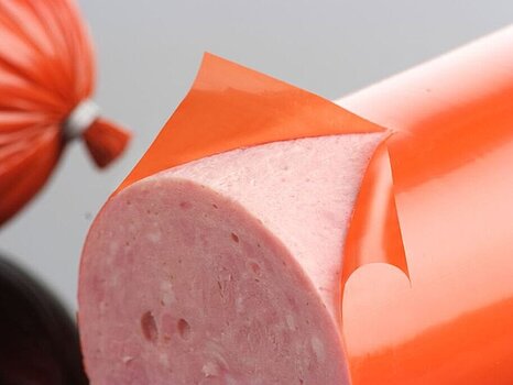 Photo d’une saucisse dont le boyau est en train d’être pelé, montrant le processus de retrait du boyau après le remplissage