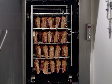 grand support métallique sur lequel sont suspendues de nombreuses pièces de viande, destinées à être cuites ou fumées